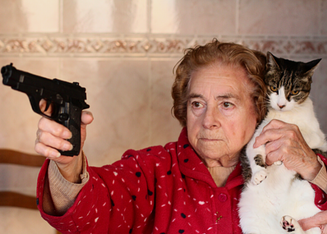 old woman holding a cat and a gun