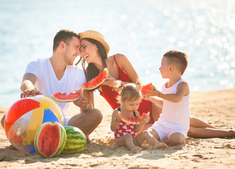 Family eating watermelon at the beach