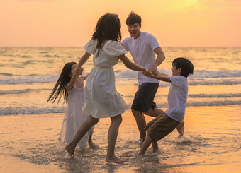 Family playing at the beach during sunset