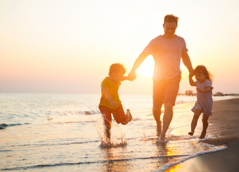 Father playing with his children on the beach one sunset