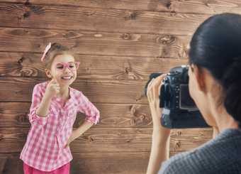 Little girl wearing pink clothes holding a pink eyeglasses during a photoshoot