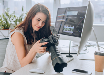 Female photographer looking at a camera while sitting in front of a computer