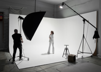 Photographer taking a photo of a model posing on a white background