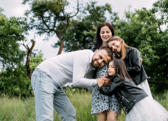 Pregnant mother, father, and two daughters poses for a photo for a maternity photoshoot
